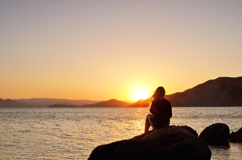 Woman Sitting on Stone Watching Sunset